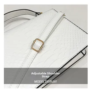 Detail of adjustable white crocodile pattern shoulder strap with gold buckle hardware