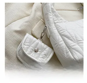 Détail d'un mini bijou de sac blanc matelassé avec attaches en métal sur un sac