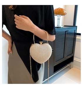 Detail of glittery heart evening clutch with round gold metal handle and chain strap