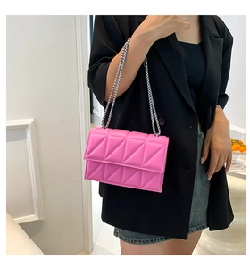 Detail of bright pink quilted crossbody bag with silver chain strap on black blazer