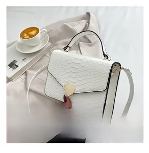 Detail of white crocodile pattern handbag featuring a gold heart-shaped metal rotary lock