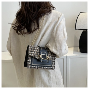 Close-up of elegant tweed plaid crossbody bag with gold chain strap on shoulder