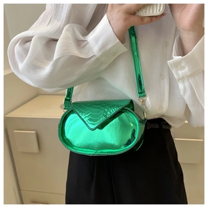 Détail du sac bandoulière ovale vert métallisé avec texture serpent et rabat magnétique