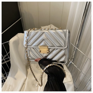 Close-up of silver quilted crossbody bag with gold metallic lock and chain strap