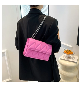 Pink quilted chain crossbody bag shown on a model with a black blazer for chic style