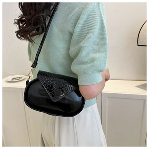Détail du motif crocodile noir sur un sac ovale brillant avec des finitions dorées