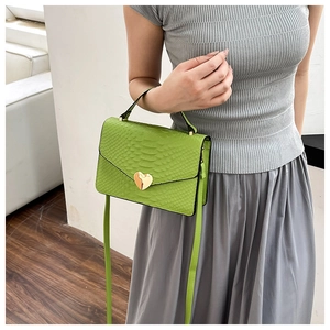 Detail of green faux snakeskin handbag with gold heart-shaped metal lock closure