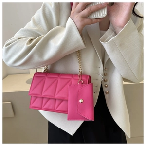 Detail der rosaroten gesteppten Klapptasche mit Goldkette und passendem Mini-Taschen-Zubehör