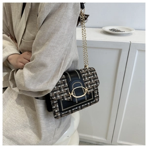 Detail of tweed crossbody bag with golden U-buckle and metallic chain strap