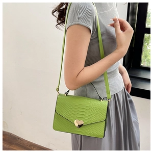 Detail of green snake pattern embossed leather bag with gold heart-shaped metal buckle