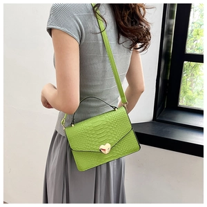 Detail of bright green crocodile embossed mini square bag with golden heart buckle