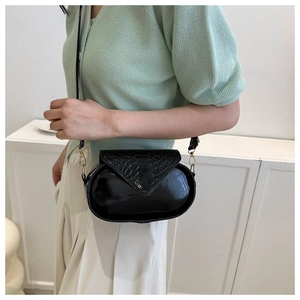 Détail du sac bandoulière ovale noir avec rabat texture croco et boucle en métal doré