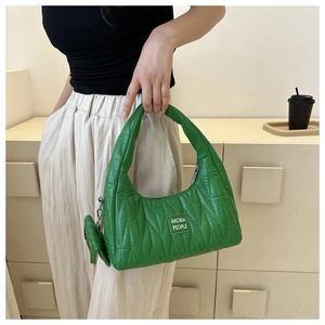 Détail d'un sac à bandoulière matelassé vert avec mini pochette et étiquette de marque