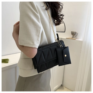 Detail einer schwarzen Stepptasche mit Goldkette und passendem Mini-Beutel an einem Modell