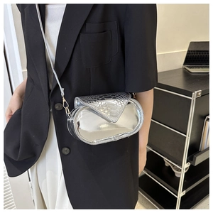 Détail d'un sac bandoulière ovale argenté avec texture crocodile porté par un mannequin