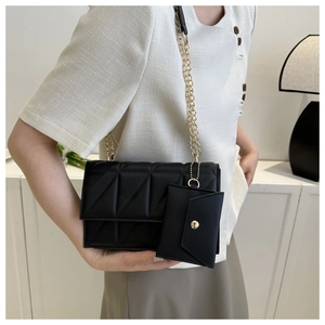 Details einer schwarzen Stepptasche mit goldener Kette und kleinem Zusatzbeutel