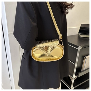 Détail du sac bandoulière capsule doré avec texture motif crocodile et finition métal