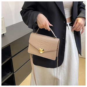 Detail of beige crocodile pattern handbag with a gold heart-shaped metal lock