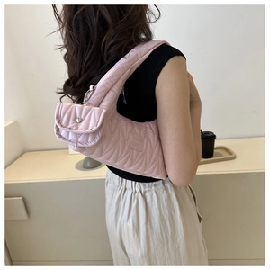 Détail du sac à bandoulière matelassé rose avec petit porte-monnaie et étiquette en tissu