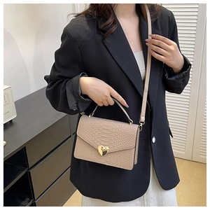 Detail of beige crocodile pattern bag featuring a stylish golden heart-shaped metal twist lock