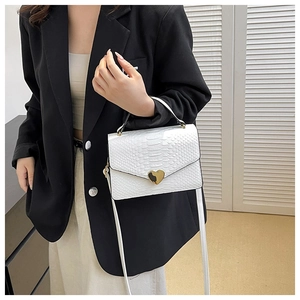 Detail of white crocodile texture leather handbag with a gold heart shaped buckle
