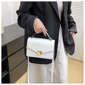 Close-up of a white crocodile texture handbag featuring a golden heart-shaped metal lock