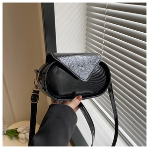 Détail du mini sac bandoulière noir avec texture crocodile et garniture dorée