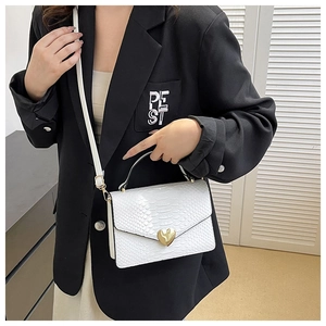 White crocodile pattern handbag with gold heart lock shown on model with black blazer