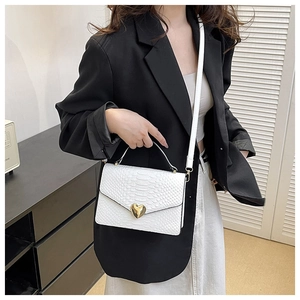 Detail of white crocodile texture leather handbag with gold heart metal clasp