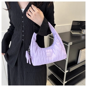 Détail du sac matelassé lavande avec logo de la marque et mini pochette amovible