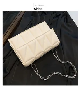 Close-up of white geometric quilted crossbody bag with stylish silver chain strap