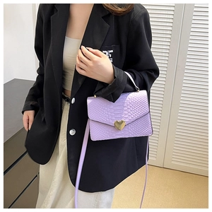 Detail of light purple crocodile pattern handbag with gold heart-shaped buckle on model