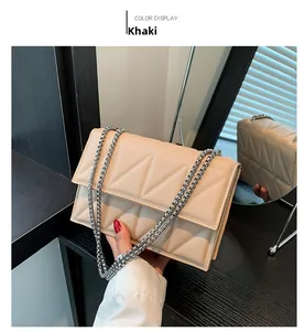 Detail of khaki quilted crossbody bag with silver chain strap and flap closure