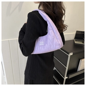 Détail du sac à bandoulière en nylon matelassé violet avec l'étiquette logo de la marque