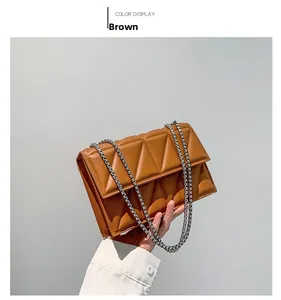 Detail of a brown quilted leather shoulder bag featuring silver chain straps and geometric texture