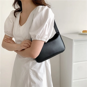 Minimalist black crescent underarm bag shown on model with smooth leather texture