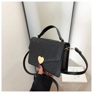 Detail of crocodile pattern faux leather handbag with golden heart-shaped metal buckle