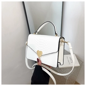 Close-up of white crocodile pattern texture and golden heart-shaped metal twist lock