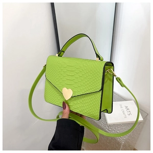 Detail of lime green faux snake leather bag featuring a gold heart lock and long strap