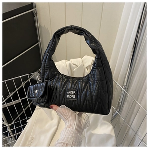 Détail du sac croissant noir matelassé avec mini pochette assortie et étiquette de marque