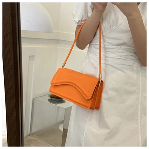 Detail van een feloranje schoudertas met een golvende flap getoond op een model