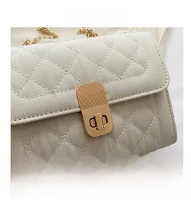 Close-up of the elegant quilted lattice pattern and golden metal twist lock on white bag