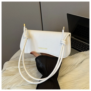 Detailed view of white crocodile pattern shoulder bag with golden text and knotted strap