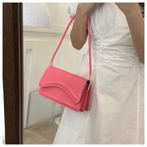 Detail van roze lederen handtas met gegolfde flap en gouden metalen accessoires