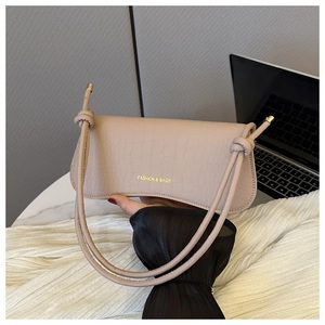 Detail of beige faux leather handbag with crocodile pattern and knotted strap accents