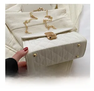 Close-up of white quilted chain bag showing golden hardware and bottom metal studs