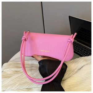 Close-up of neon pink crocodile pattern shoulder bag with stylish knotted handles
