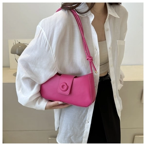 Detail of rose pink leather underarm bag with knotted strap and magnetic flap closure