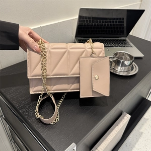 Elegante beige gesteppte Umhängetasche mit Kette und passender Geldbörse auf dem Schreibtisch