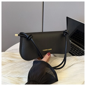 Detail view of black crocodile pattern faux leather handbag with gold metal accents